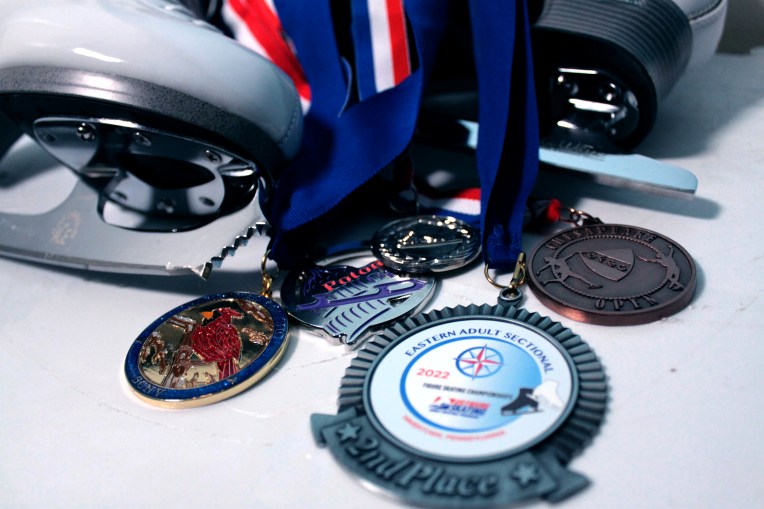 Image of a figure skate lying on its side with five medals draped over it.